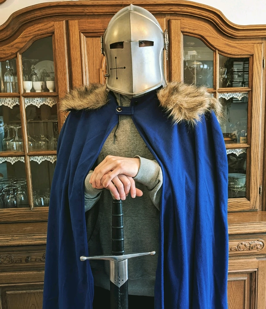 Ritter mit blauen Umhang, mit einem Fantasy Helm wie der des Wardens in dem Spiel For Honour. Hat einen Pulli statt Rüstung 