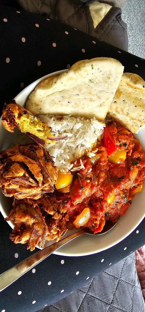 Homemade chicken tikka masala curry with big onions and red peppers, and thick onion bhagis broken open to expose the onions.