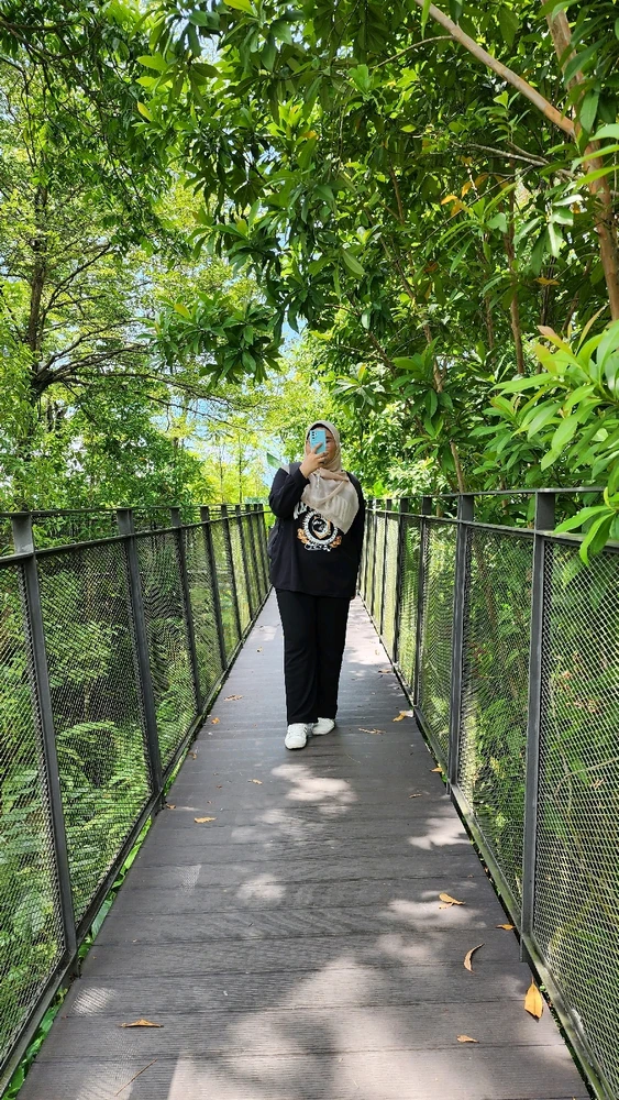 A girl on the bridge taking pictures, surrounded by trees and leaves 