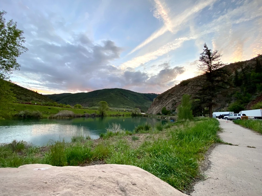 A lake sits in a mountain depression as the sun sets the sky glows blue and a slight golden hue 