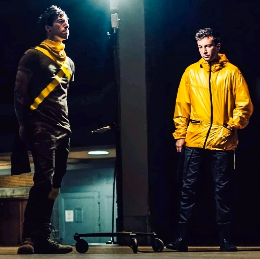 Josh Dun in his Torchbearer outfit on the left, Tyler Joseph in a yellow rain jacket on the right.