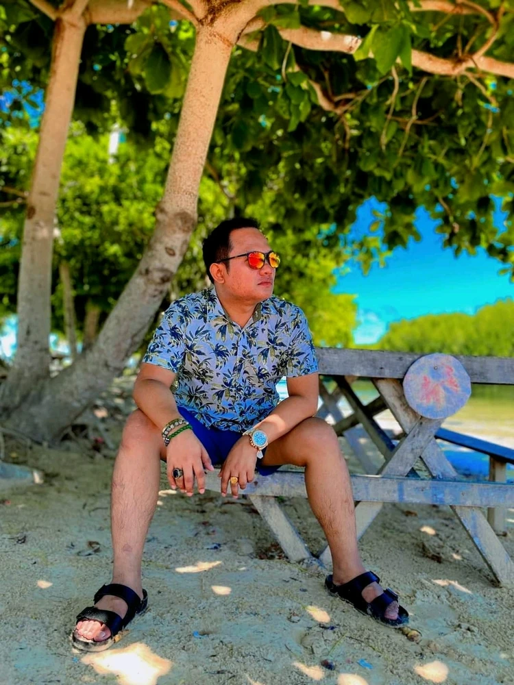 Beautiful man seating on the beach watching sea birds fly.