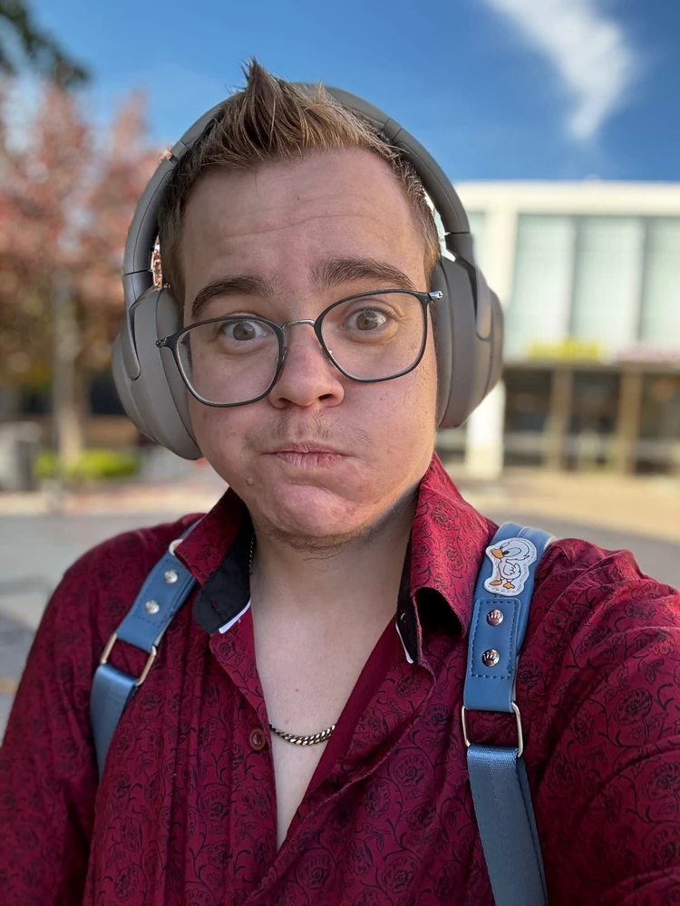 White 30 year old male with short blonde hair and round glasses making a funny face in the camera. 