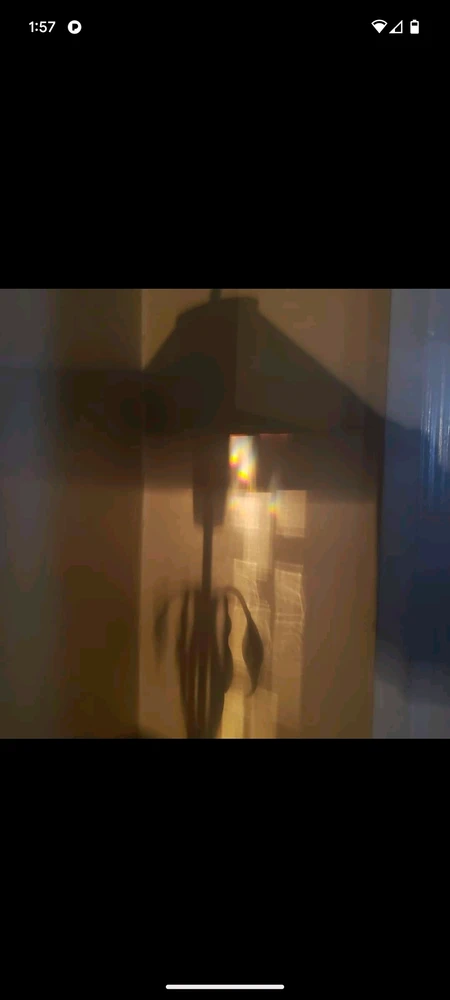 Light and rainbow patterns on a wall that appear to be falling from the shadow of a lamp