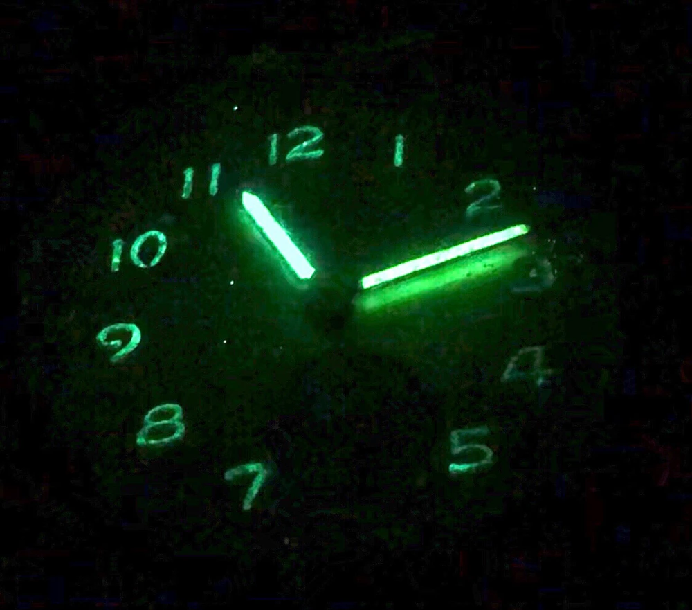 A watch face with ghoulish green glowing hands and numbers. Digitally brightened to show the numbers more clearly