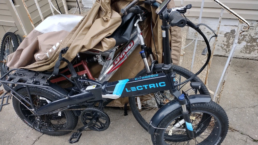 An e-bike and a more traditional mountain bike partially obscured by an all weather bike cover.