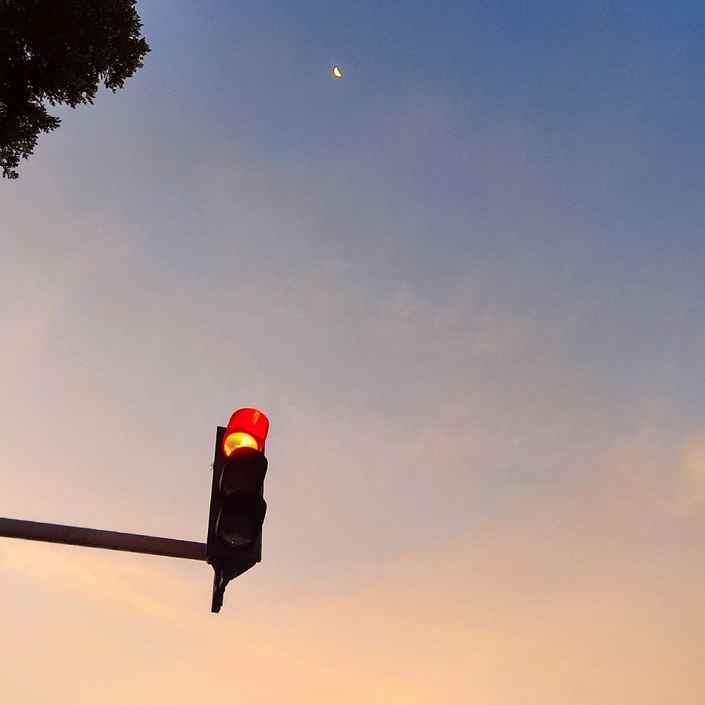 Traffic Light in red sing, sunset background with the moon 