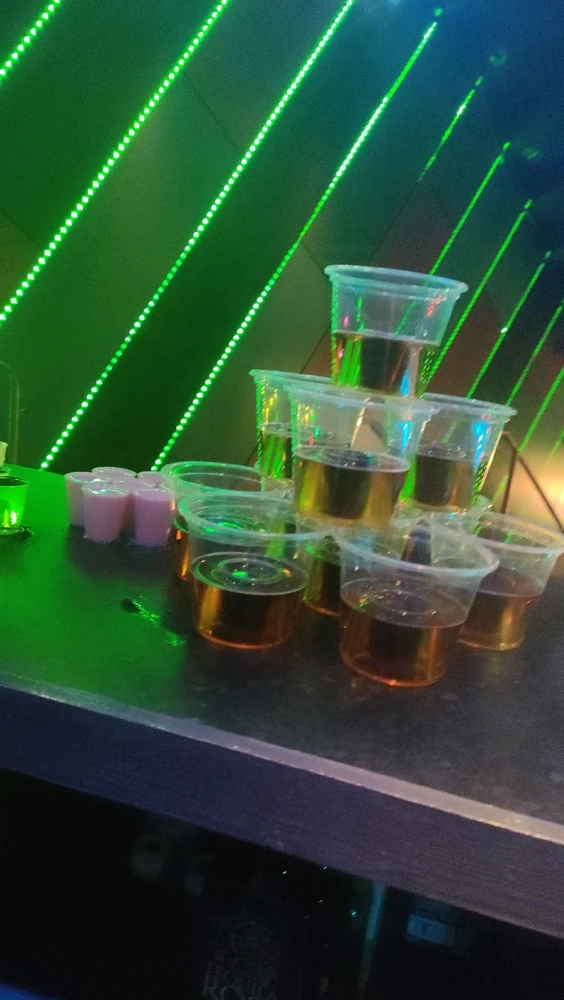 A stand filled with shot glasses with various liquors and a stacked tower of jaeger glasses.
