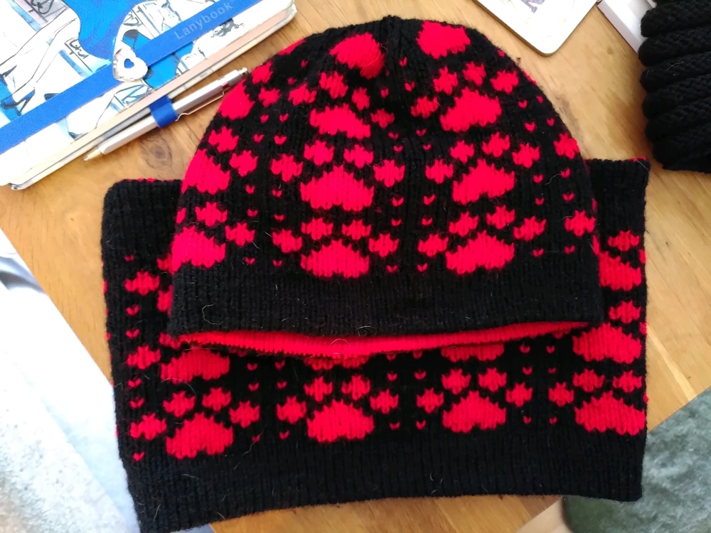 Black hat with red paw prints on top of a black cowl with red paw prints 