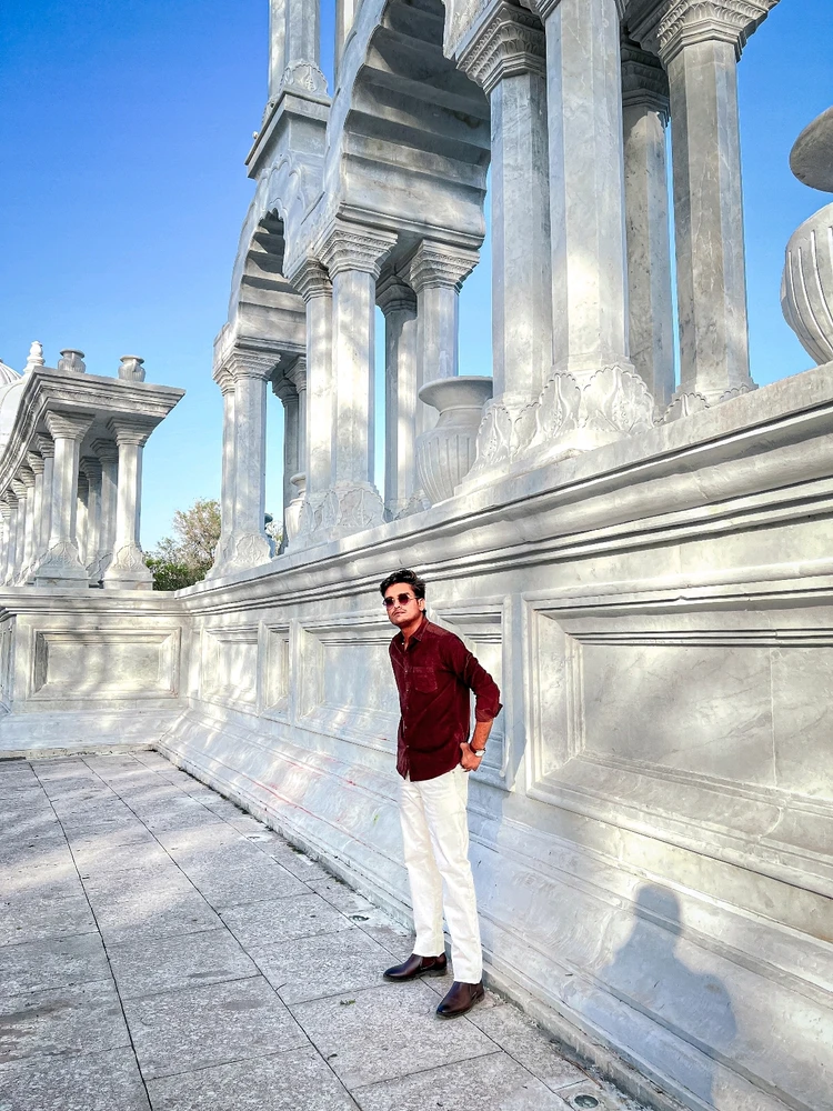 A handsome man standing in front of beautiful white monument...