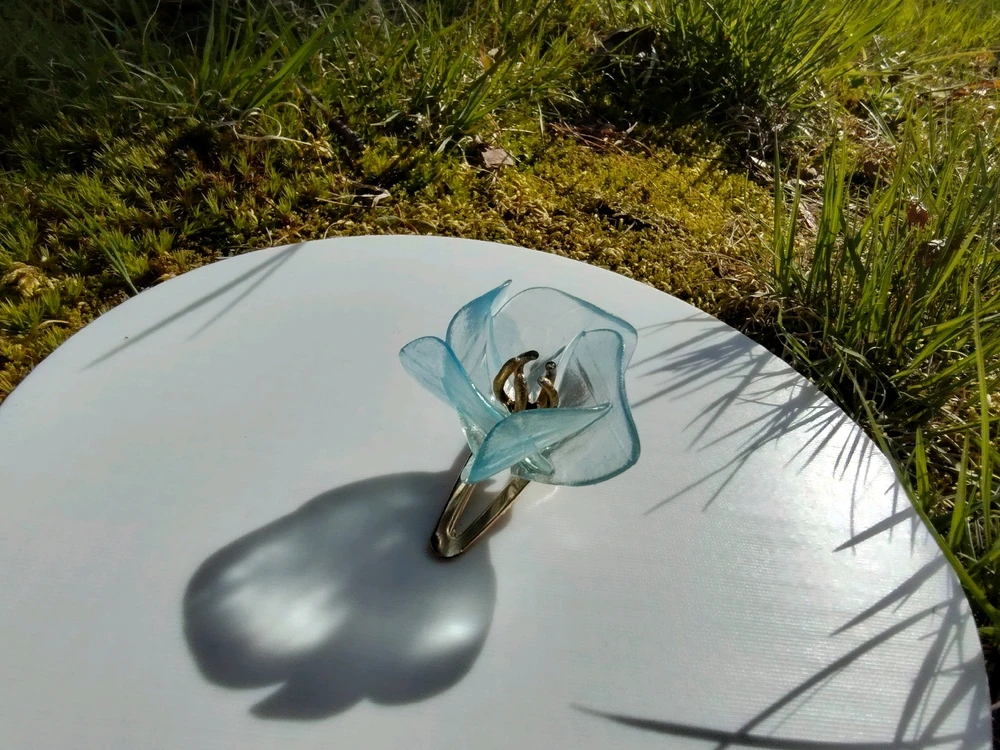 A translucent blue flower sits glued upon a golden barrette. The pistils are painted a warm gold.