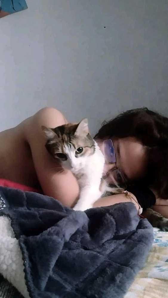 Mi persona recostada sobre la cama, boca abajo y abrazando a mi gatita. 