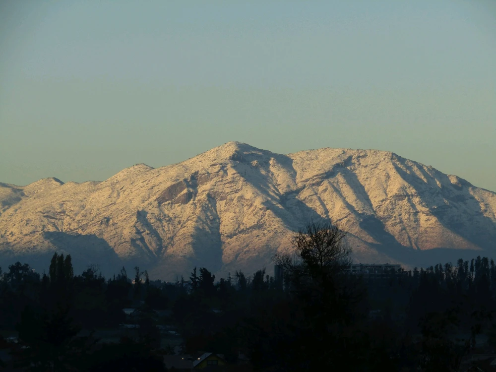 There is a clear light blue sky. The middle is a zoom into the Andes covered in snow with the sun hitting on its peaks♥️