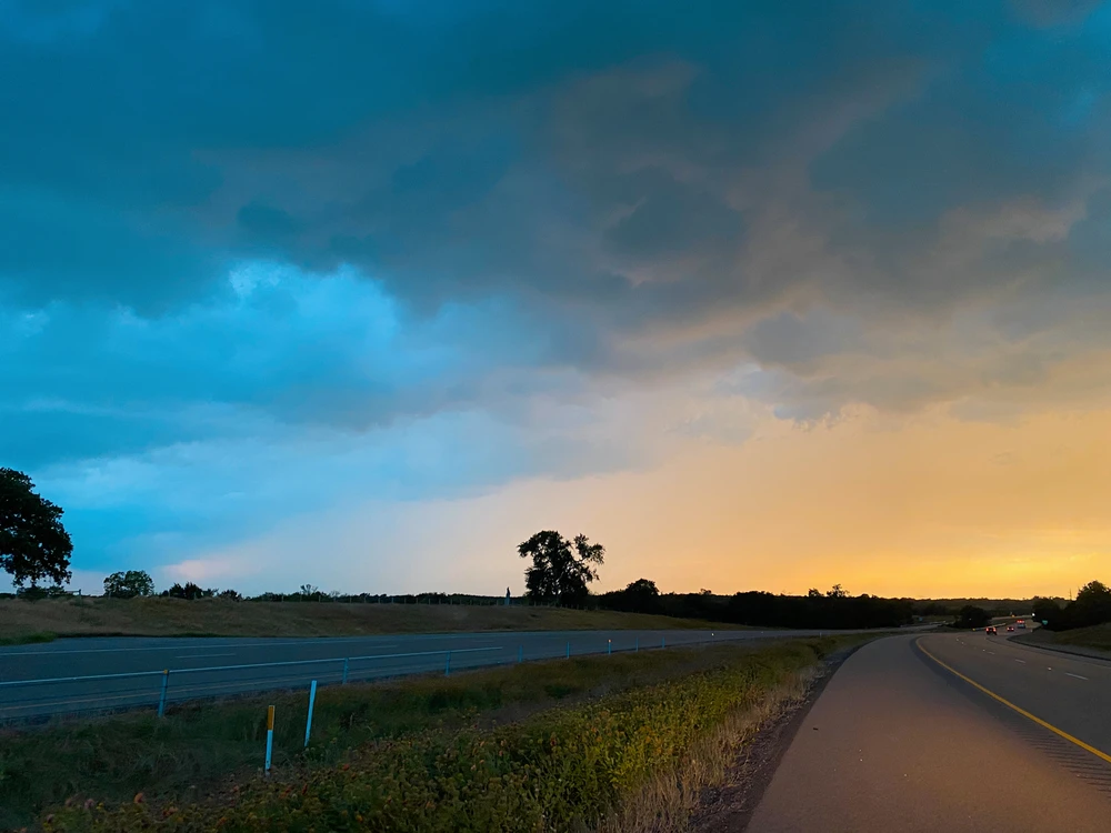 picture of a sunset over a street view. There are rain clouds all around.
