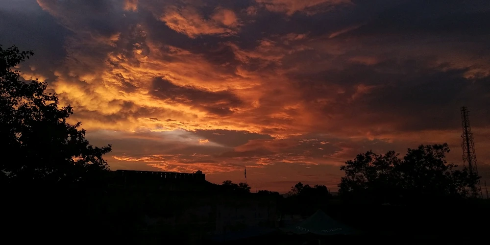 The setting sun whispers secrets to the night, leaving behind a trail of memories etched in the sky.