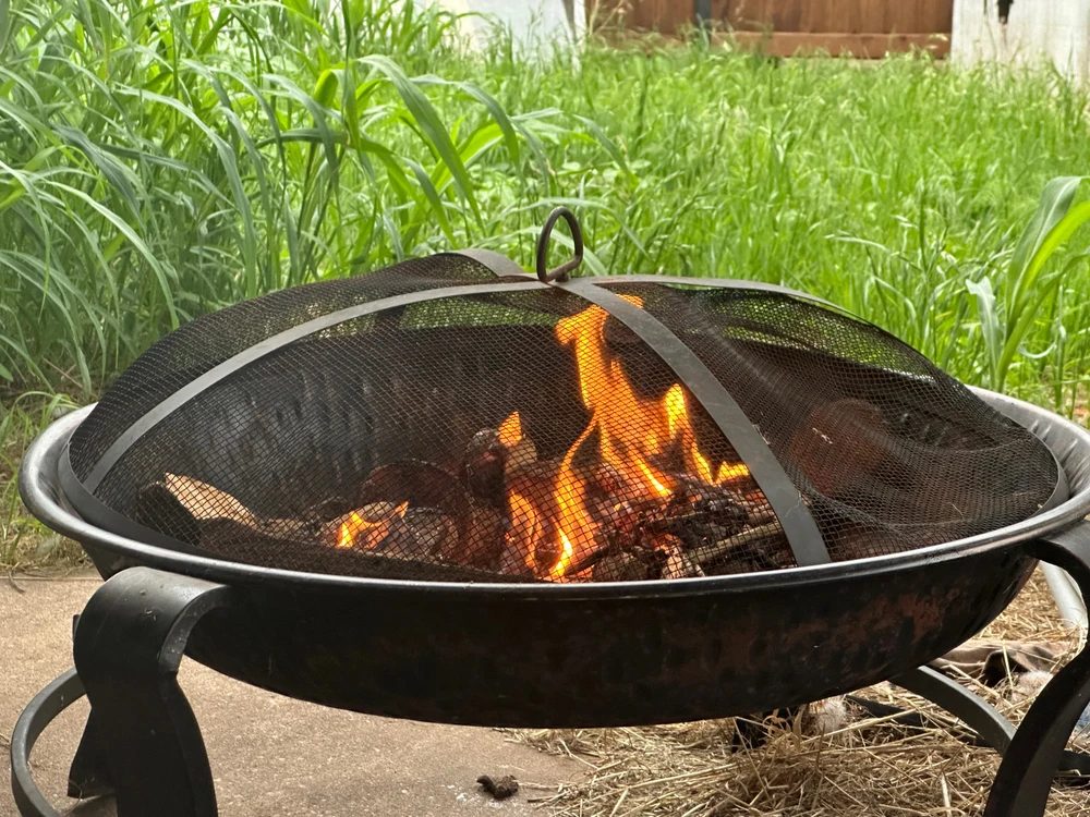 A fire is burning in the backyard. A fire pit has a fire going.