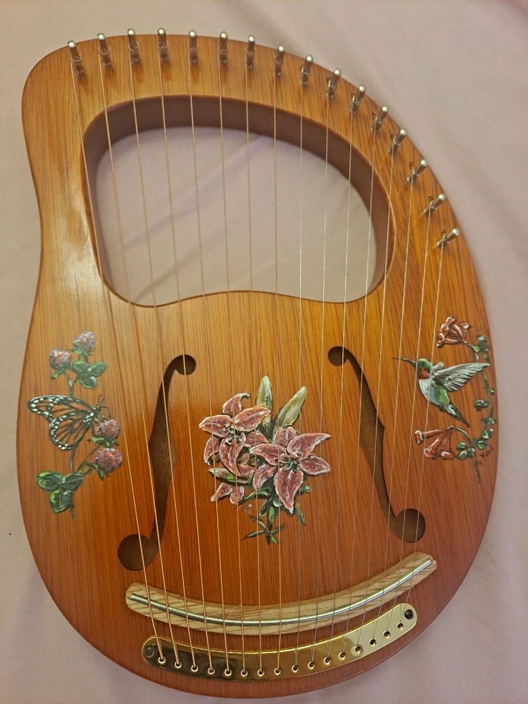 A small handheld wooden harp with ornate flowers painted onto the wood
