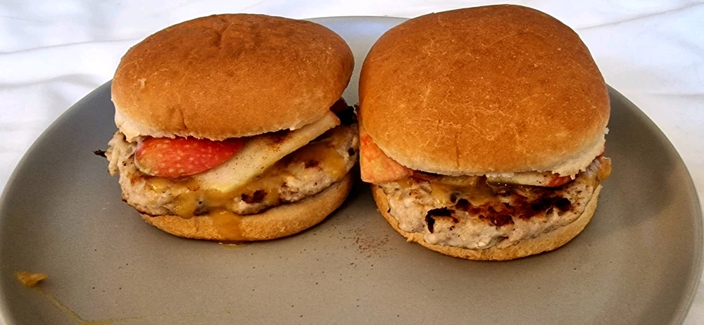 Two apple chicken burgers chilling on a plate. 