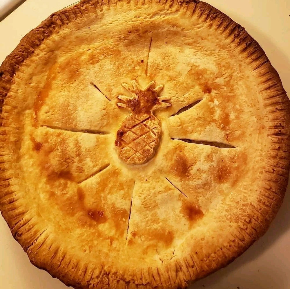A whole baked pineapple pie with a pineapple motif on the crust