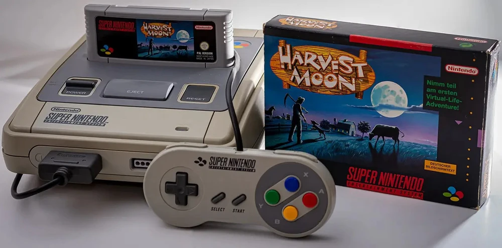 Super Nintendo mit eingestecktem Harvest Moon Spielmodul, Controller und Harvest Moon Pappkarton.