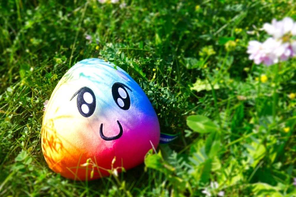 Roztomilý plyšák Rainbow Gooberta ze hry Backpack Battles, ležící v zelené trávě