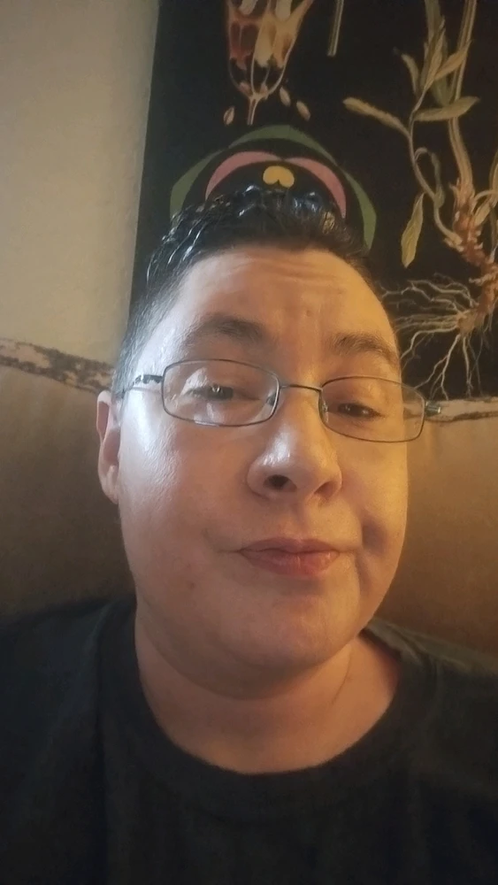 Tempest, hair and glasses soaked from the rain, smirking a bit