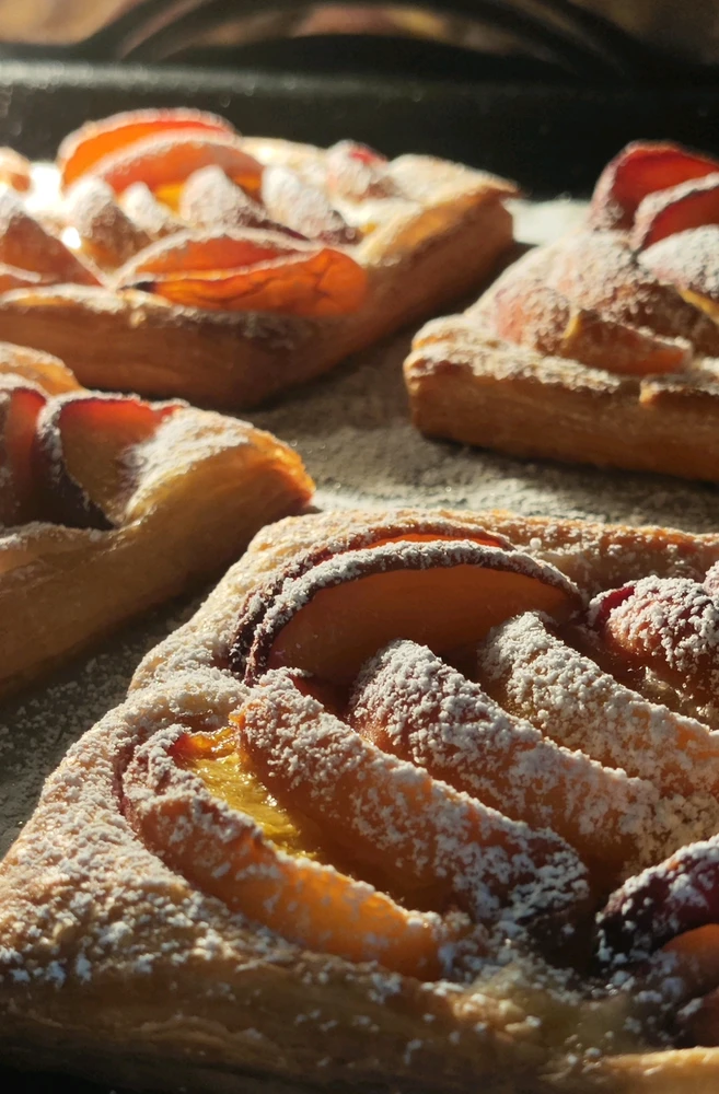 the photo shows peach puff pastry tarts sprinkled with powdered sugar on top