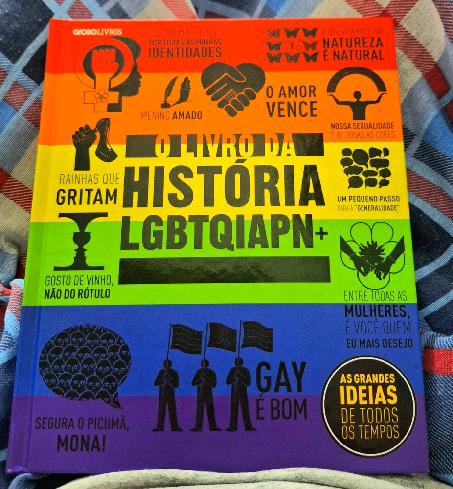 O livro da história LGBTQIAPN+, capa dura colorida com as cores do arco-iris e decorada com referências à comunidade LGBT+.