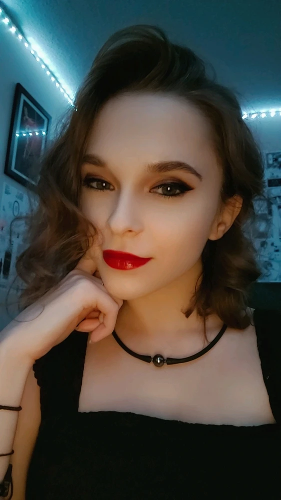 Selfie of a woman with red lipstick in her bedroom. 