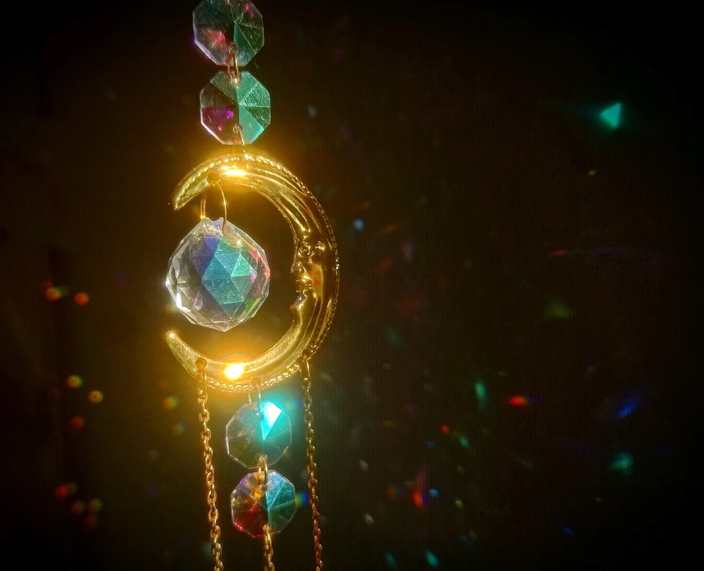 eine bearbeitete Fotografie von einem Sonnenfänger, Dekoration die Lichter reflektiert. Ein goldener Halbmond mit Kristallen