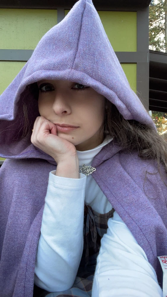User selfie wearing a lavender cloak with the hood up.