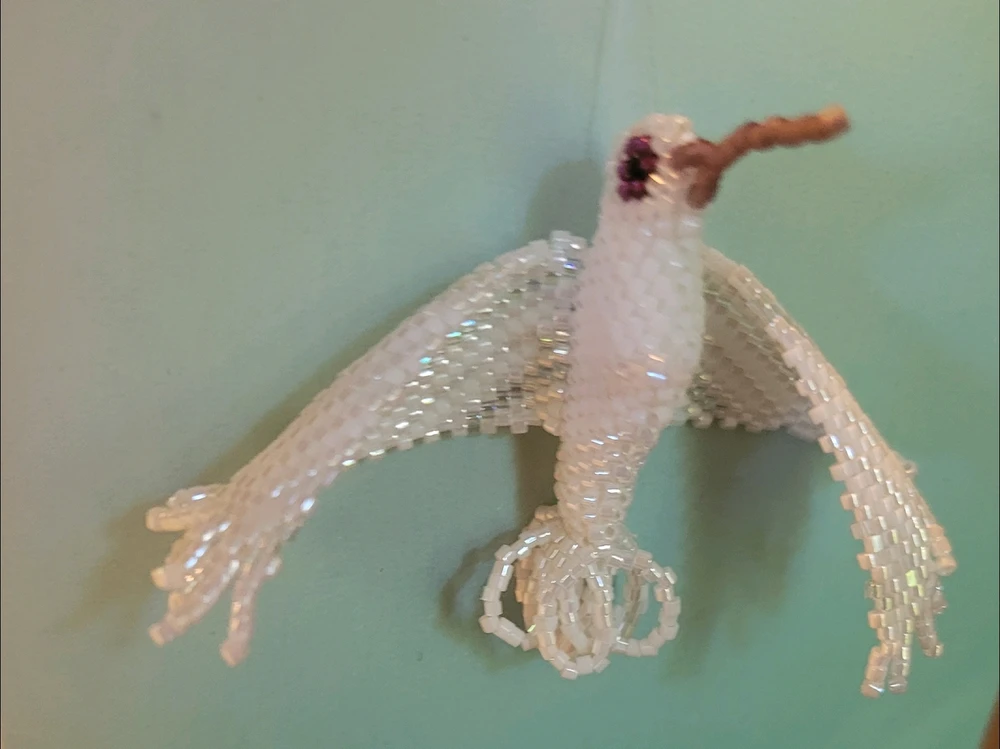 White beaded hummingbird against blue background 