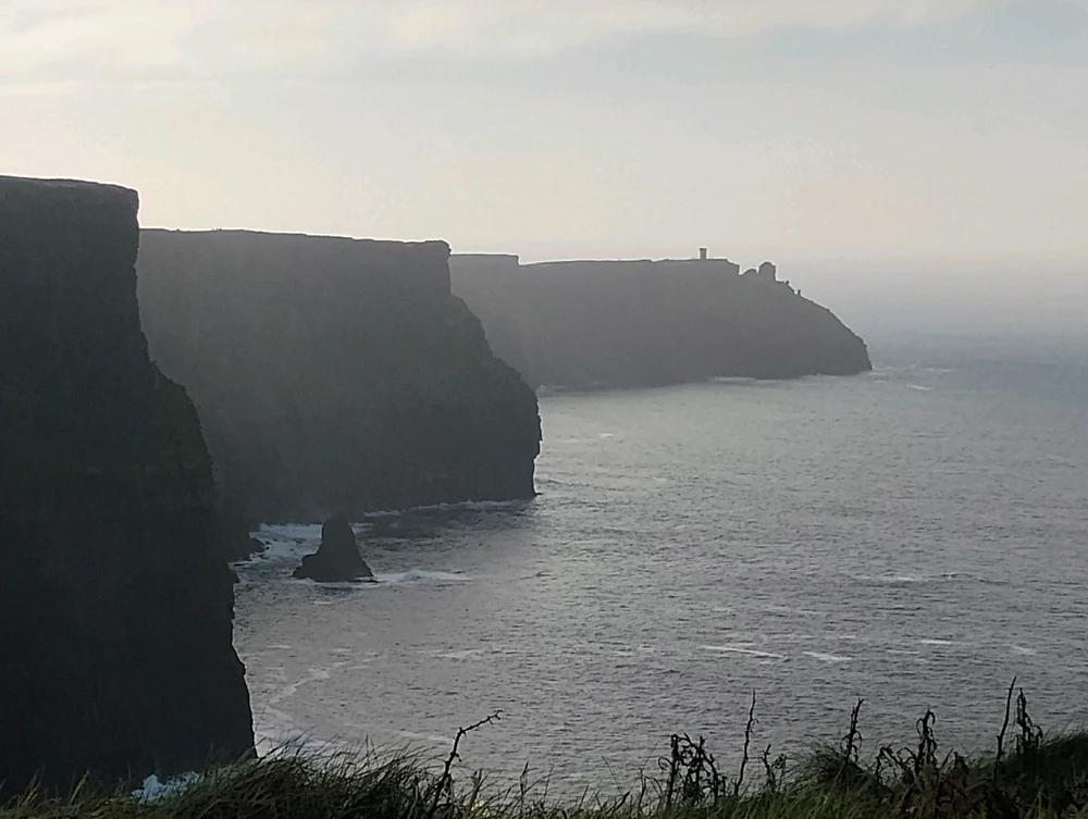 Cliffs of Moher in Galway, Ireland. The cliffs jut out into the water as the surf below crashes against the stone.