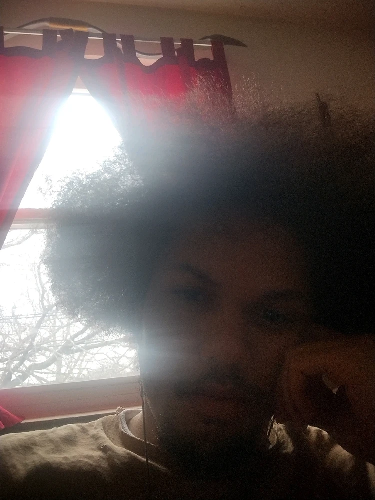 A selfie with hair visible messy, clarity is blown out by the sun overexposing the image through the window behind me.