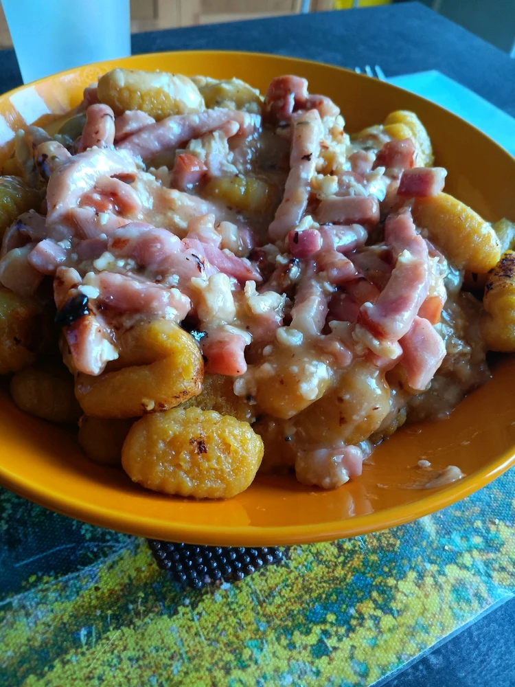 Gnocchis de courge plongés dans un camembert fondue et lardons