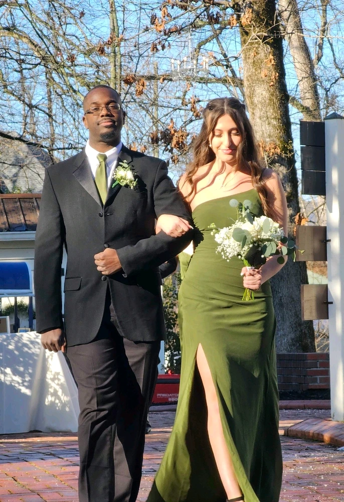 A well dressed black man in a black suit, white shirt and green tie, next to a gorgeous woman in a olive green dress.