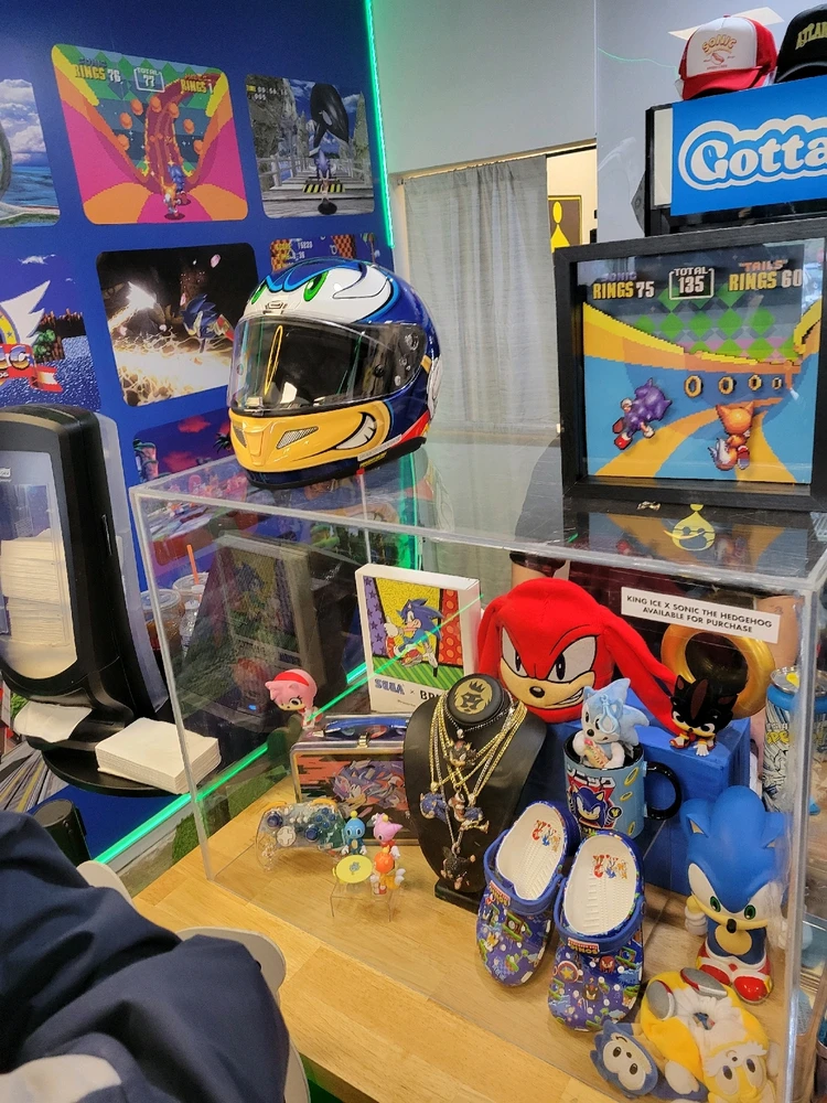 A fast food cafe, filled with Sonic the hedgehog merch. There's a theme Sonic Helmet, gold chain, and lunchbox