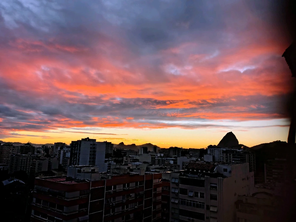 the sun is coming up! the city is still dark and the silhouette of the mountain is set against yellow and pink lights