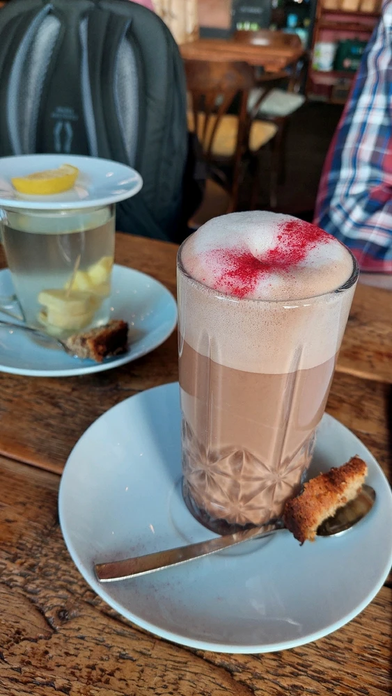 Frischer Ingwertee und Chai-Latte mit Erdbeerpulver als Dekoration. Dazu Kuchen-Stücke statt Kaffee-Kekse