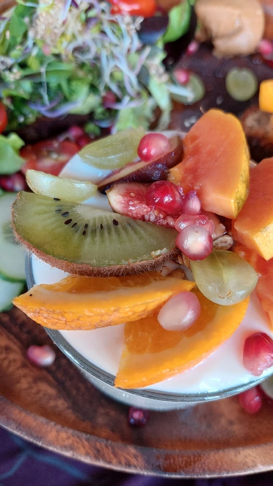 Frischer Joghurt mit richtig viel Obst drauf, schön dekoriert. Im Hintergrund die Avocadostulle.