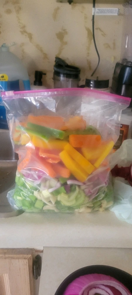 Prep bag of celery, red onion, multicolor bell peppers, and carrots.