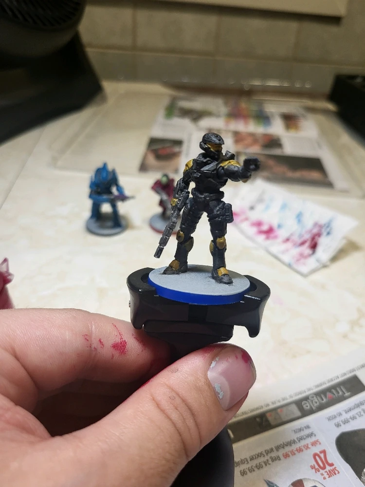 A Spartan Mark 7 for Halo Flashpoint holding a rifle and pointing. This one has been painted gray and gold. From the front.