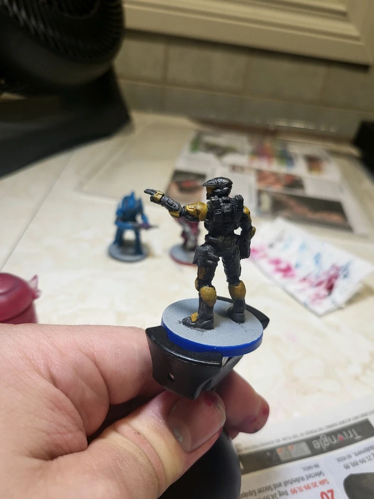 A Spartan Mark 7 for Halo Flashpoint holding a rifle and pointing. This one has been painted gray and gold. From the back.