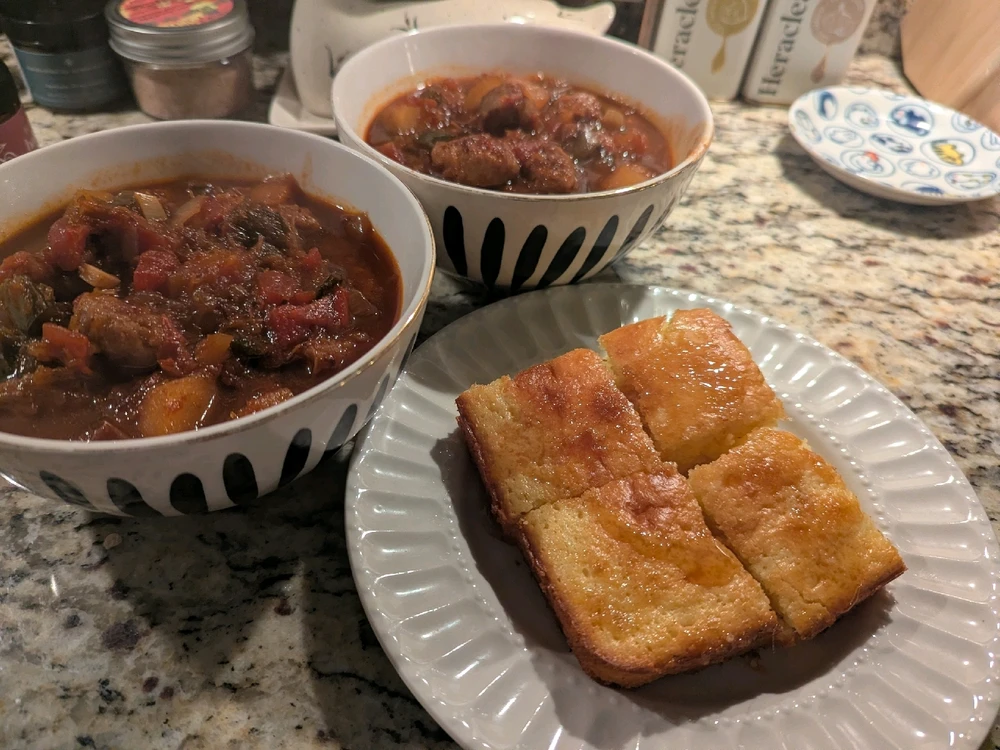 Two bowls of stew and cornbread with hot honey