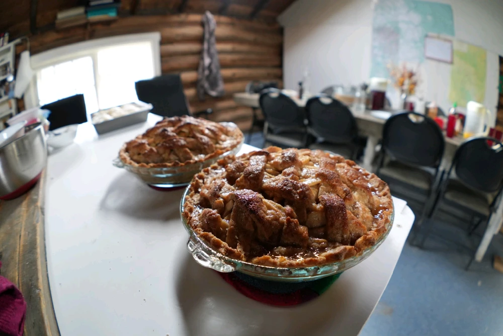 A couple of lattice crust apple pies in a cabin setting, sugar sauce poured on top which caramelizes