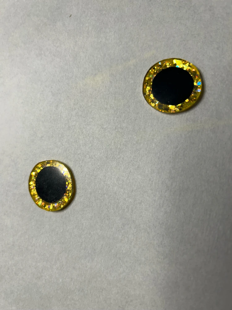 Eyes made from shrink plastic, painted with acrylic glitter, backed by felt, topped with resin, and buggy as they should be.