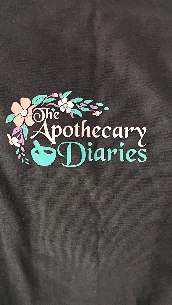 La camiseta por delante, el logo de la serie de los diarios de la boticaria, en la zona del corazón.
