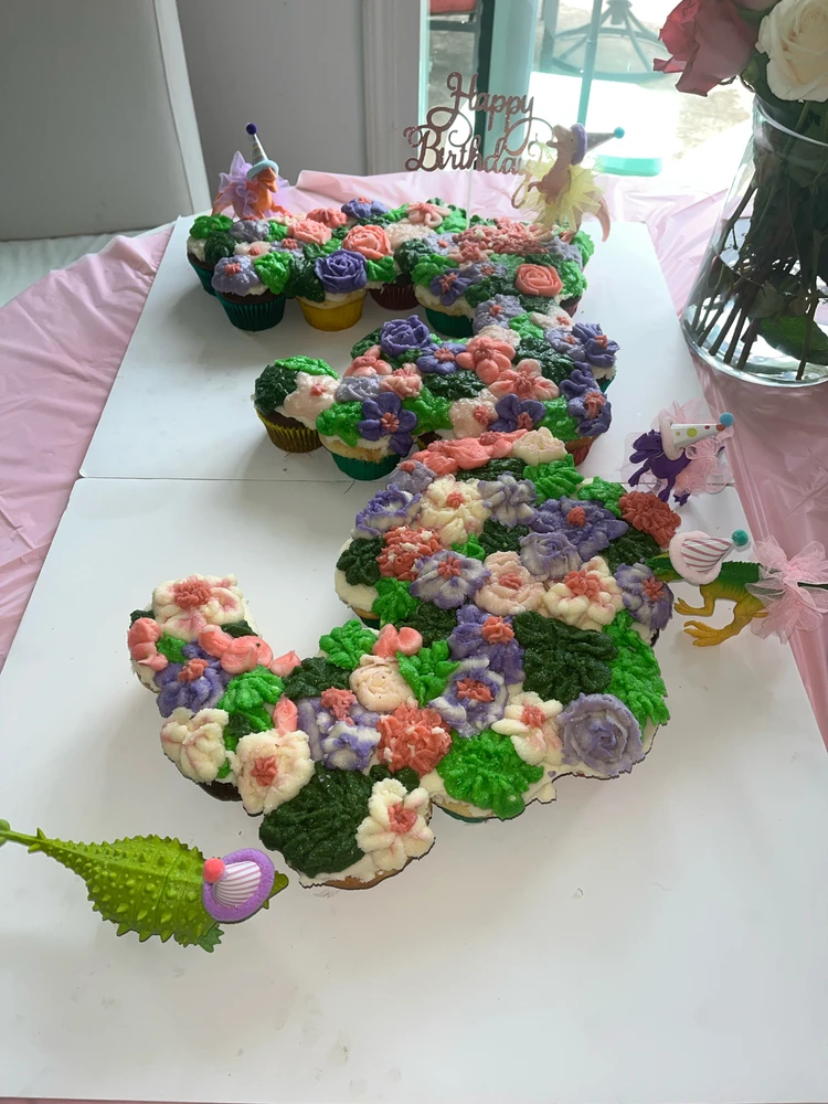 Chocolate and vanilla cupcakes are arranged in the shape of a three, frosted with buttercream flowers