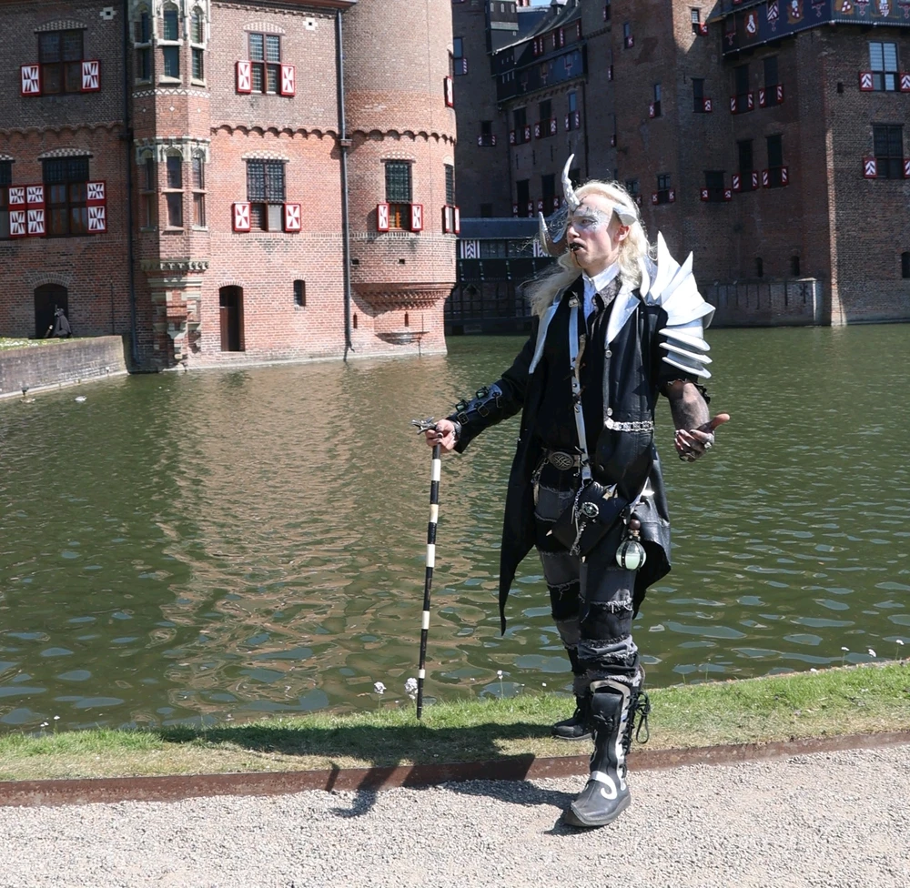 My original character, a vampire dragon dentist posing in front of a medieval castle.