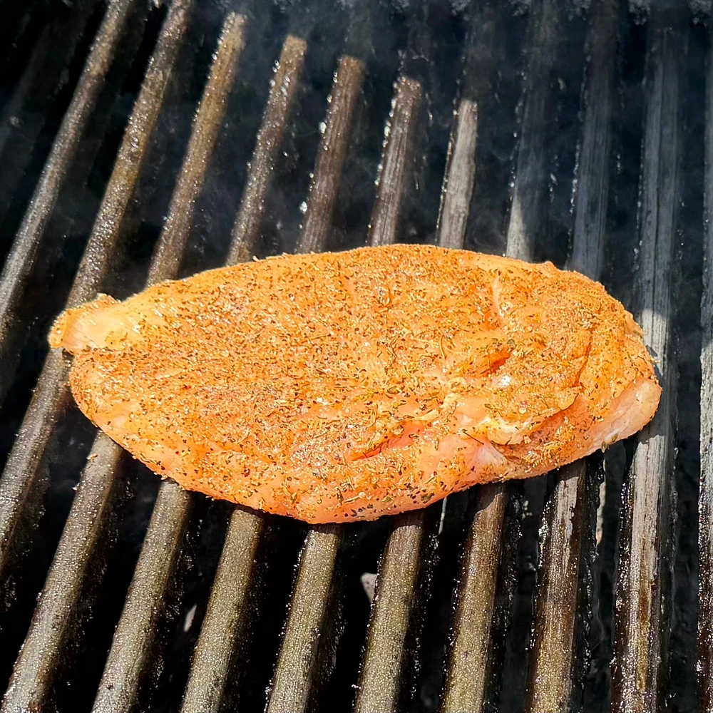 Seasoned chicken breast on a grill